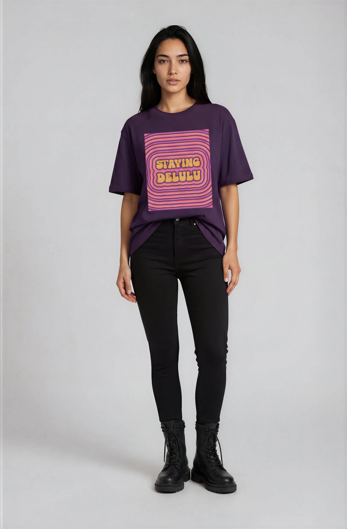 Person wearing a purple t-shirt with pink graphic design on a plain background